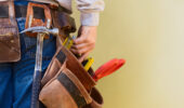 A young construction worker reaches into his tool belt. Copy Space.